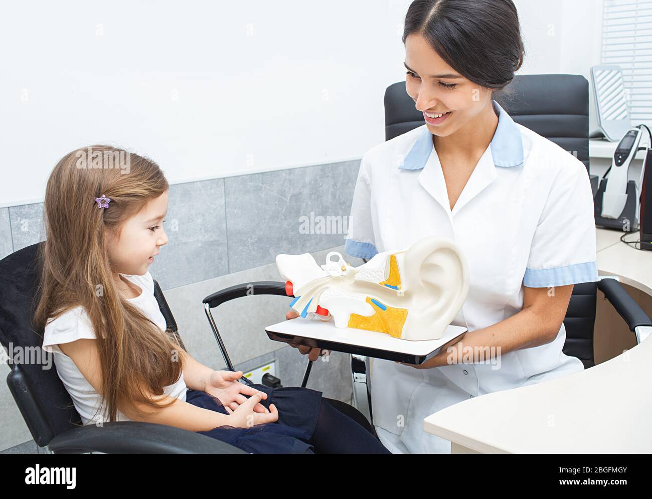 Audiologist showing a little girl ear structure on a model of a human ear. Hearing clinic Stock Photo