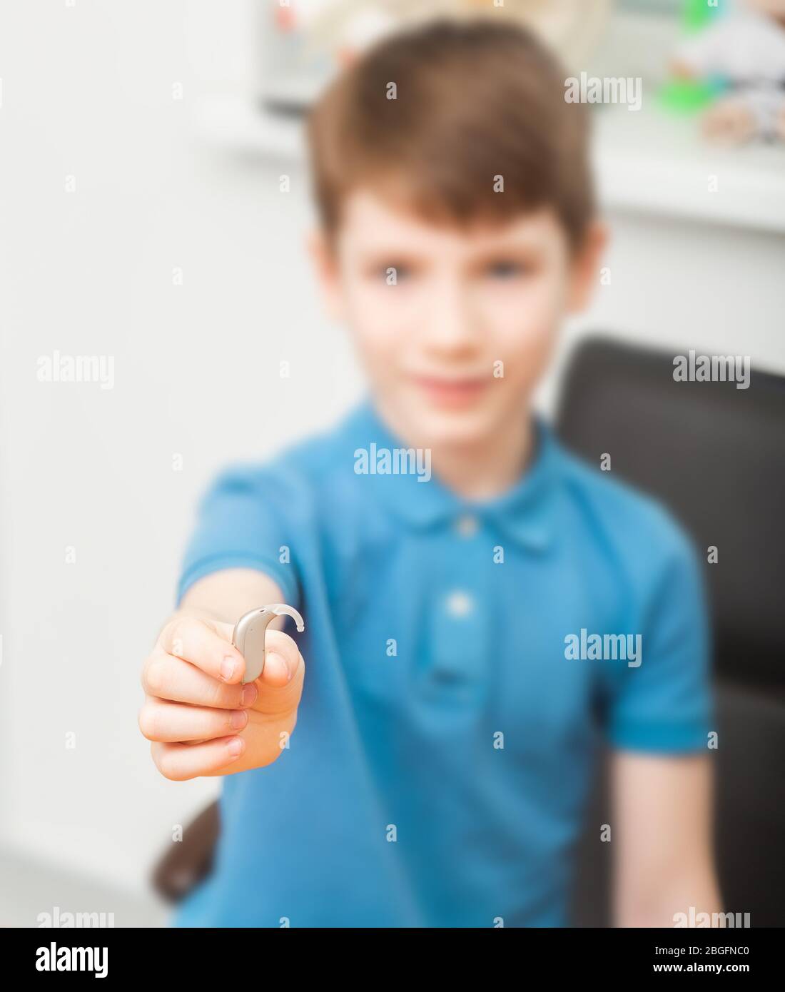 Child holding in his hand a hearing aid that will help him hear the sounds of the world. Hearing aid close-up Stock Photo