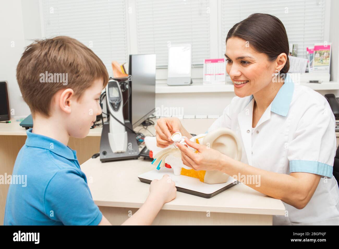 Audiologist showing a boy patient an eardrum on model of human ear. Complaints of bed hearing in children Stock Photo