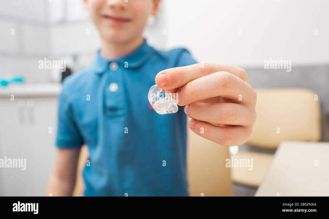 Hearing aid and earpiece in a patient's boy hand closeup. Hearing clinic. Ear prosthetics Stock Photo