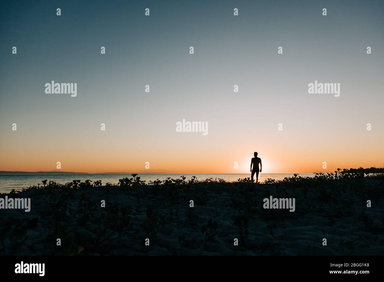 Silhouette of a man enjoying sunset on the beach Stock Photo