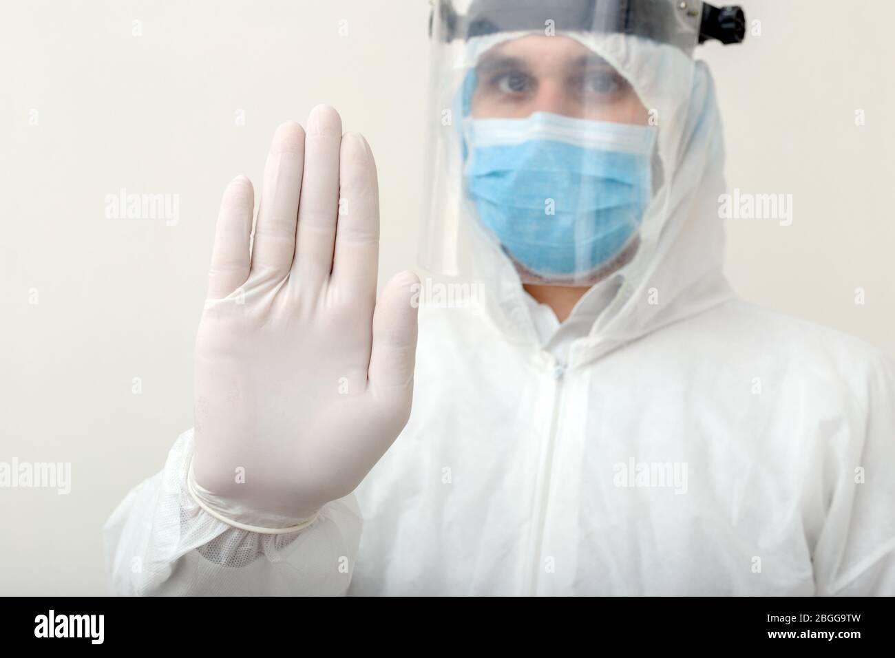 Doctor show sign Stop gesture NO to pandemic of Covid-19, Coronavirus wearing protection suit and face mask on white background. Medical, healthcare Stock Photo