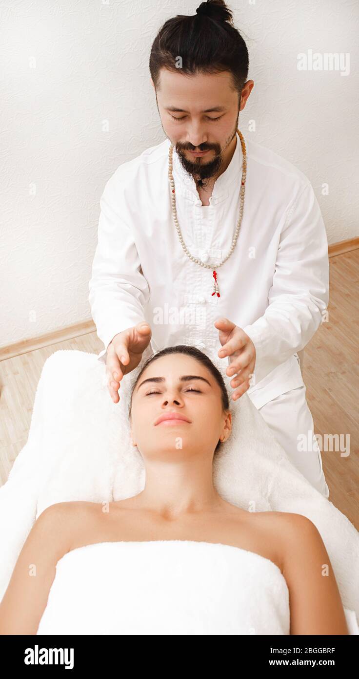Chiropractor doing energetic head massage. Woman getting reiki therapy. Alternative medicine Stock Photo