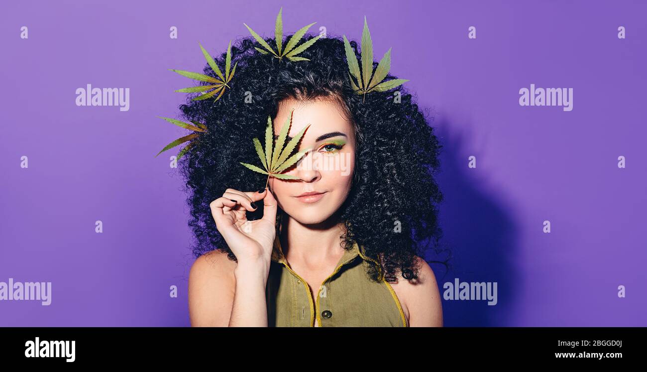 Mixed race woman with Afro-curls holding hemp Leaf. The concept of legalization of marijuana and Cannabis Stock Photo