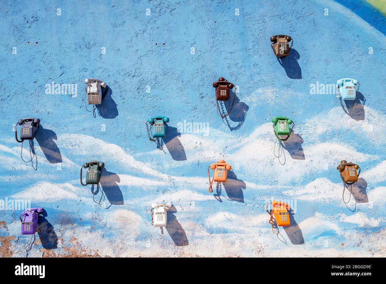 A lot of vintage, colorful telephones hanging on the blue wall in Morocco Stock Photo