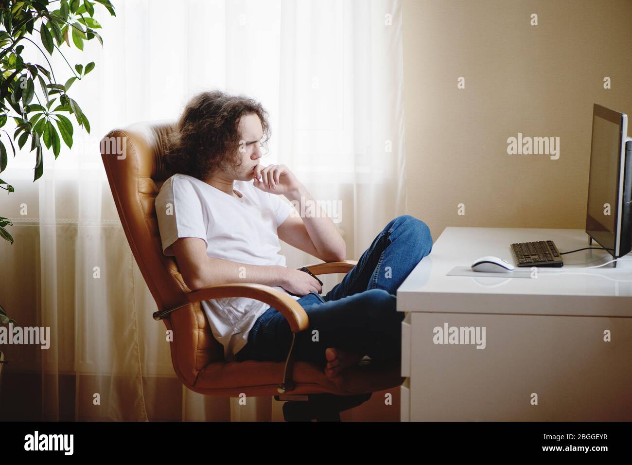 Teenager sitting on chair and concentrated studying at home attending online classes. Stock Photo