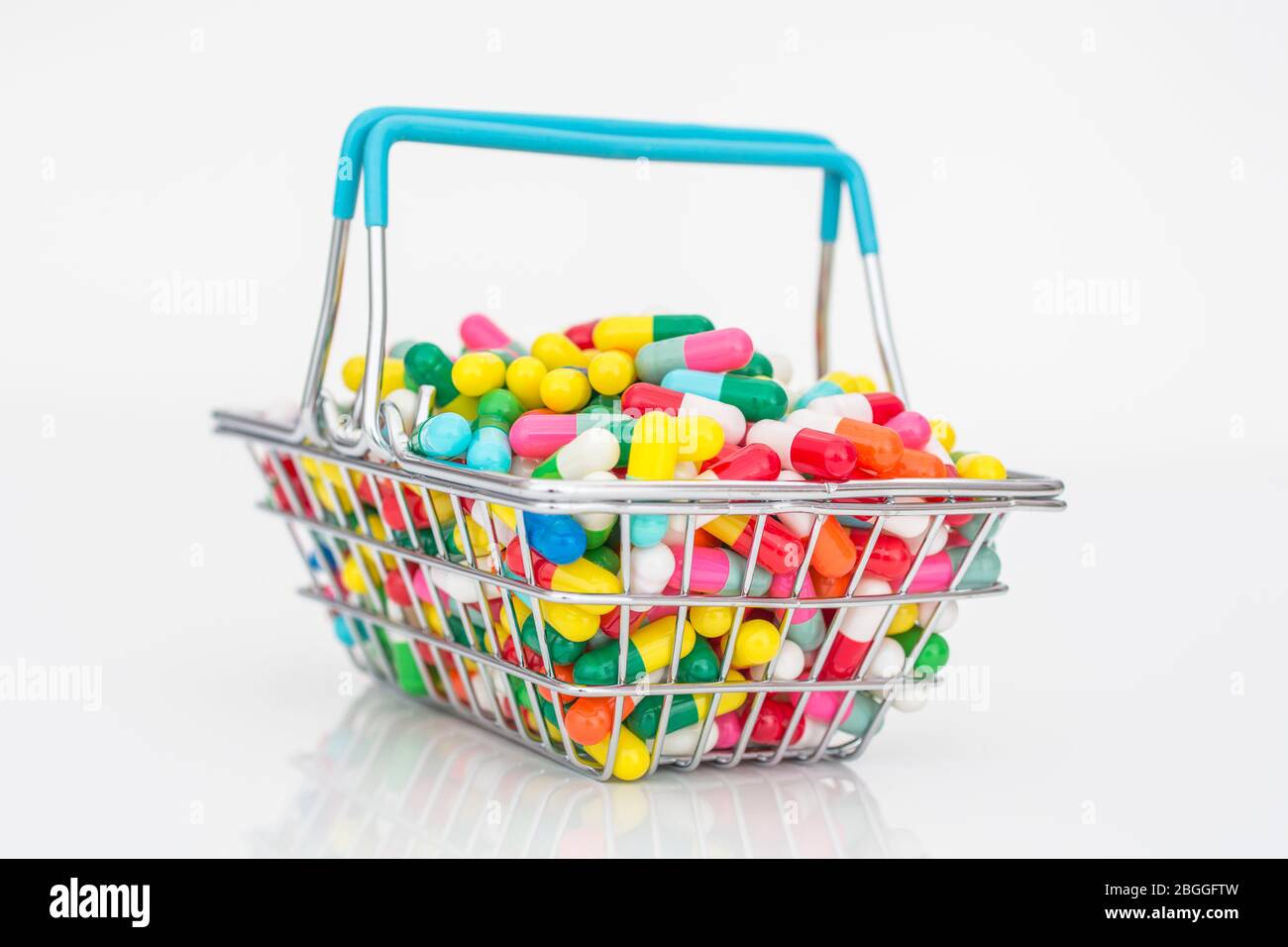 Mini shopping basket full of colourful pills caplets. For Big Pharma
