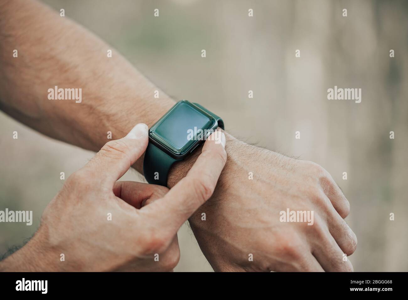 Macro concept of man clicking, pointing on a screen of his generic design smart watch, blurred background Stock Photo