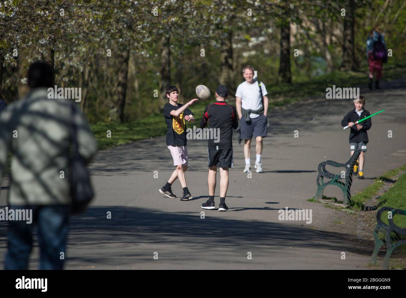 Glasgow, UK. 21st Apr, 2020. Pictured: People take their daily exercise in the park in the form of ball games such as passing a rugby ball back and forth. Scenes from Kelvingrove Park in Glasgow during the coronavirus (COVID-19) lockdown. Credit: Colin Fisher/Alamy Live News Stock Photo
