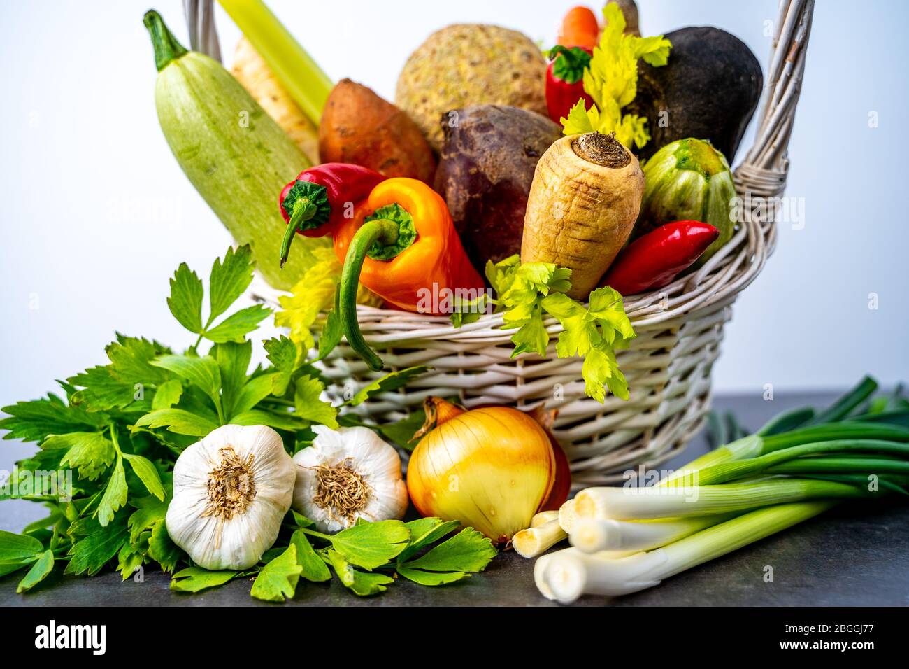 Yellow onion and garlic head next to basket with root vegetables Stock