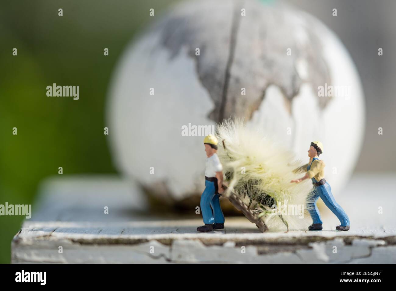 Little people carry off a dandelion flower on the roof of a vintage birdfeeder Stock Photo