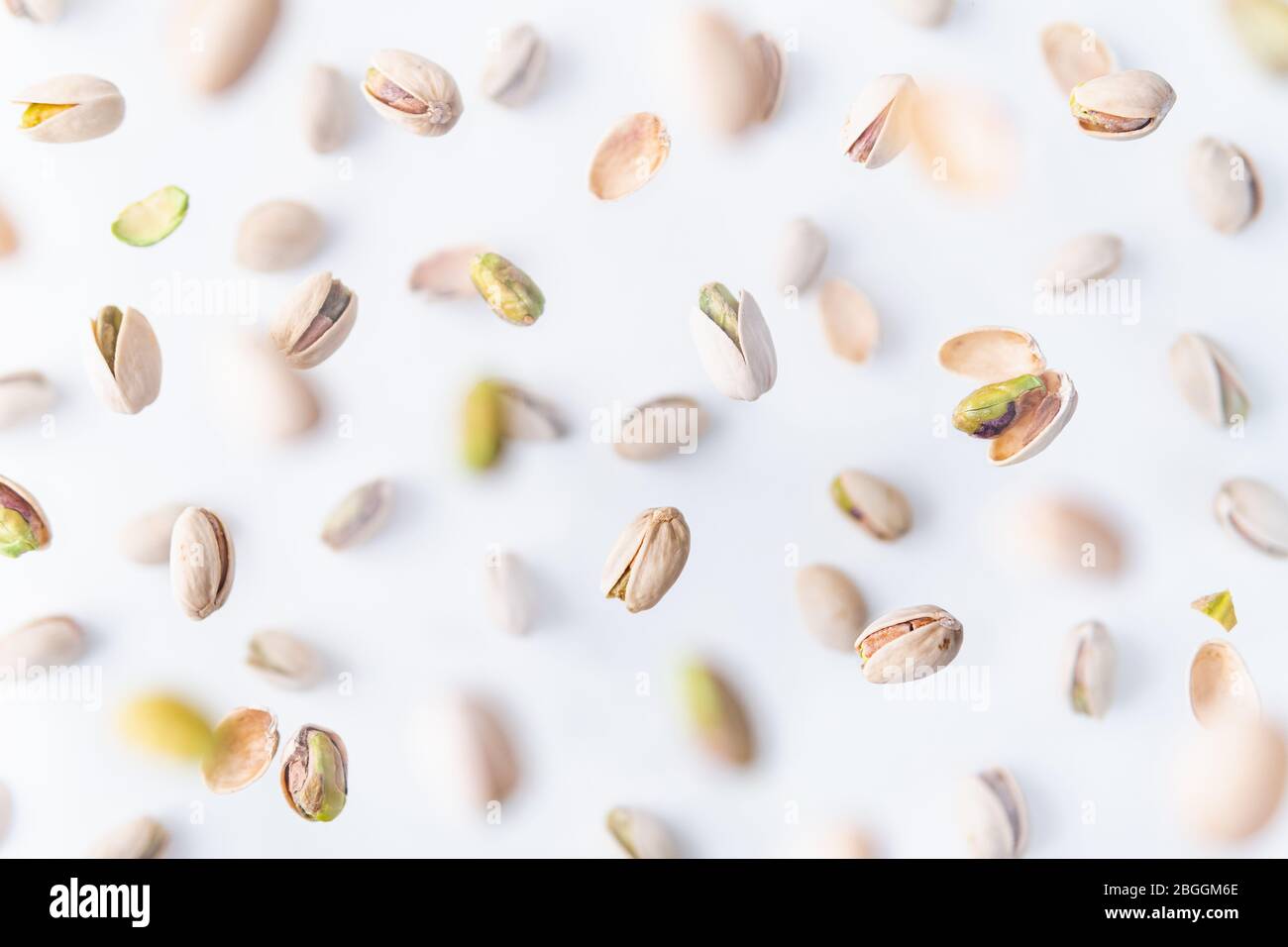 In shell pistachio nuts flying above white background, levitation effect. Stock Photo
