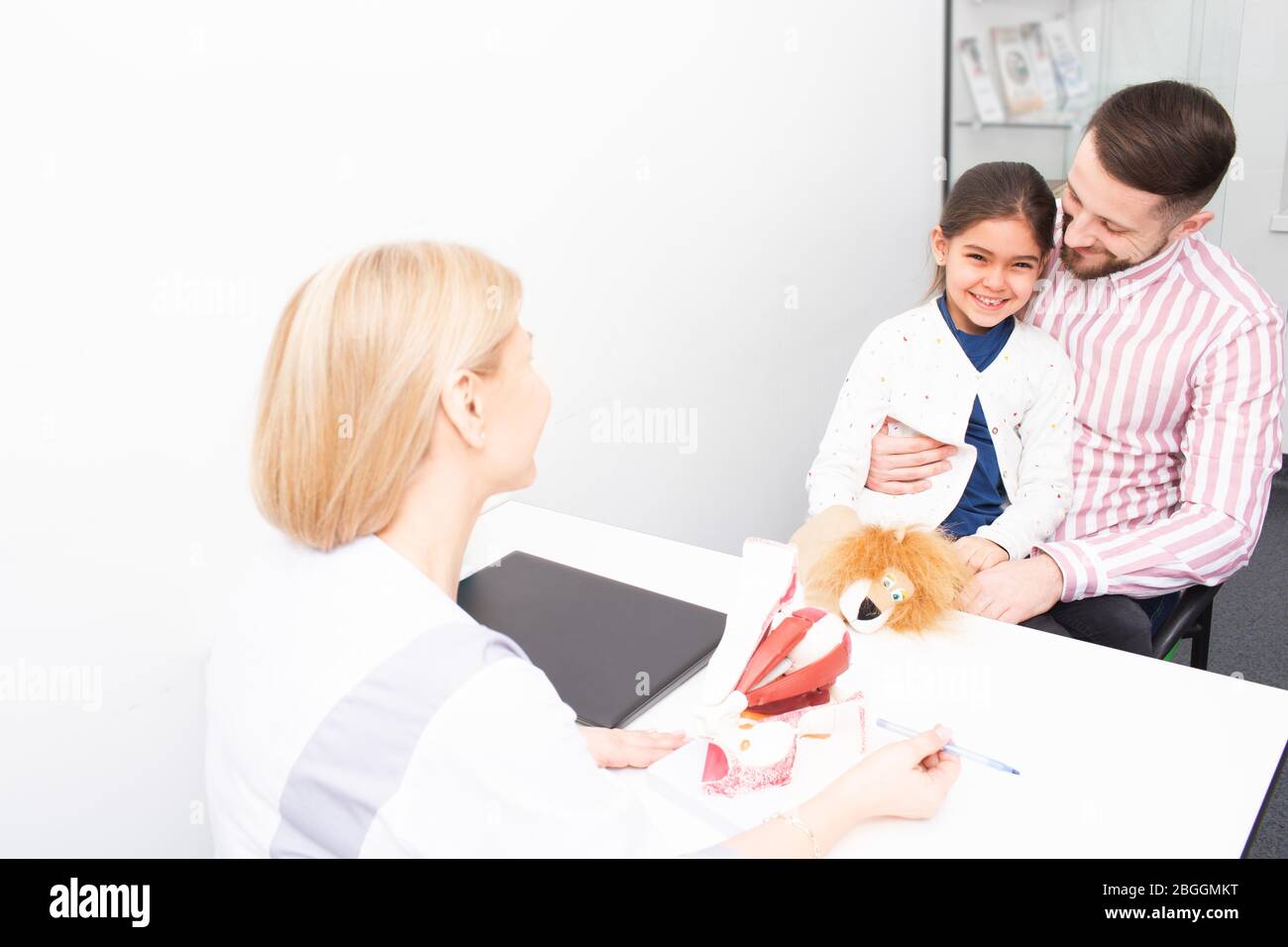 Dad and his daughter in office of an ophthalmologist. Girl smiling and not afraid of eye test. Optometrist consultation Stock Photo