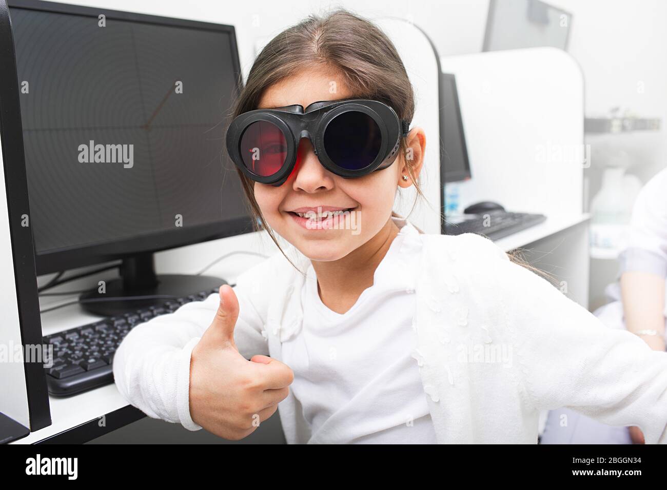 Little girl likes to receive computer treatment for her eyes. Strabismus treatment. Amblyopia treatment. Stock Photo