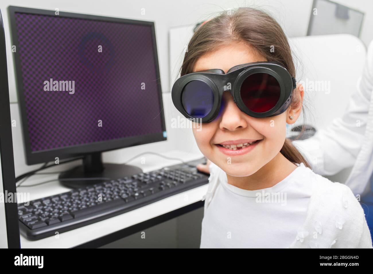 Little girl likes to receive computer treatment for her eyes. Strabismus treatment. Amblyopia treatment. Stock Photo