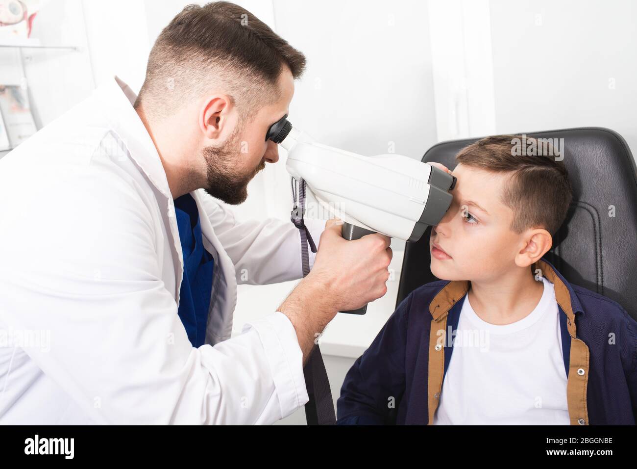Male optometrist doing eye examination of boy patient. Manual tonometer for measuring intraocular pressure. Vision correction Stock Photo