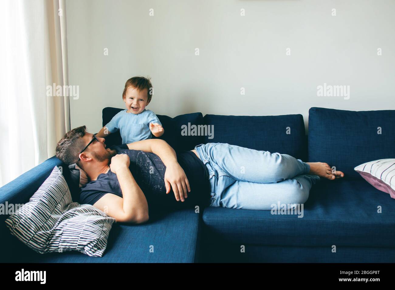 Dad is playing with his son. The baby is laughing. The concept of communication between dads and children, entertainment in quarantine, stay at home. Stock Photo