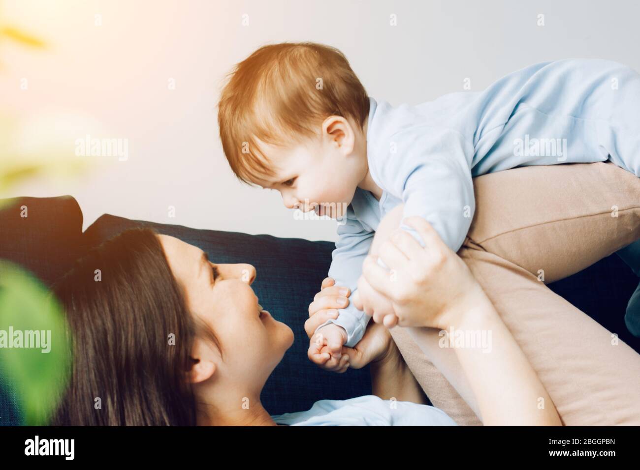 Mother is playing with her son. The baby is laughing. The concept of communication between parents and children, entertainment in quarantine, stay home. Stock Photo