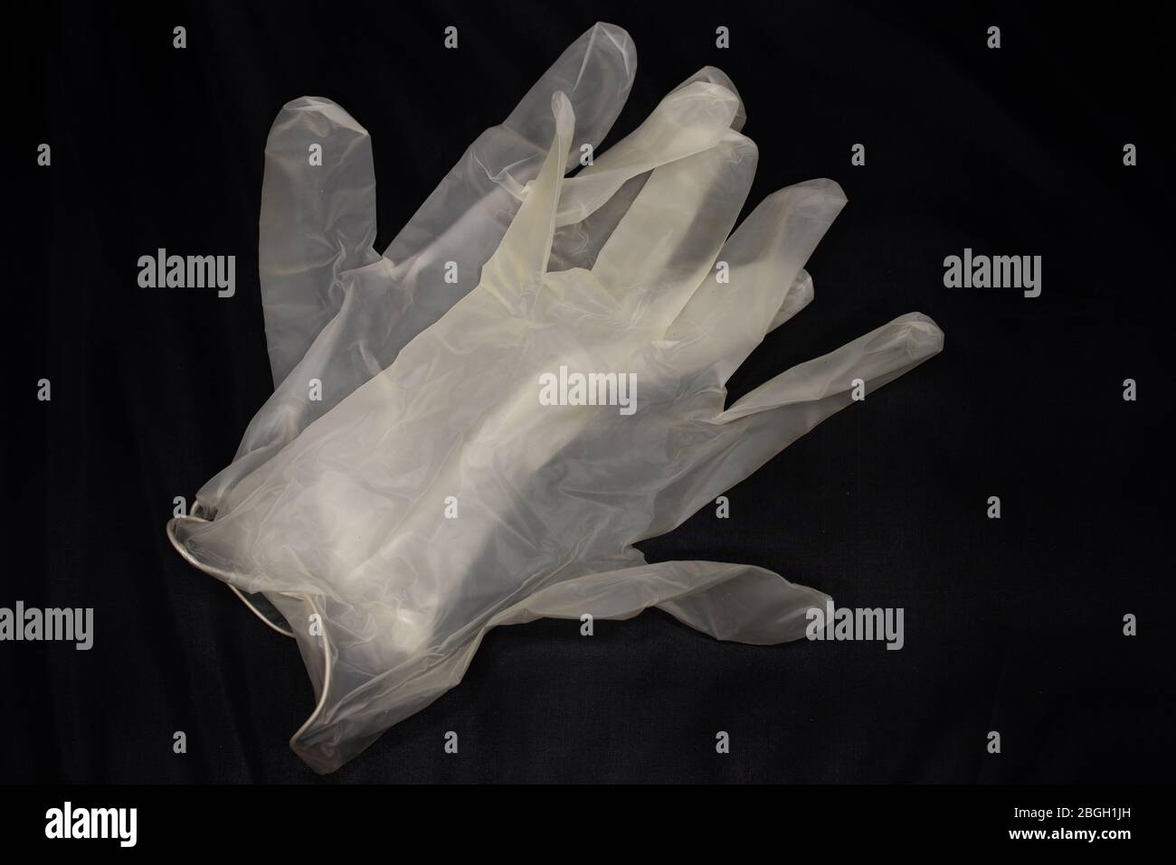 A pair of clear latex medical gloves isolated on black, for use in surgery and for protection from flu and other viruses, including coronavirus. Stock Photo