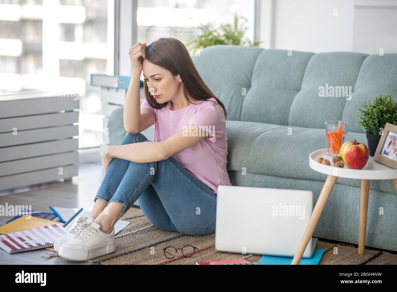 Dark-haired young woman sitting on the floor at home. Stock Photo