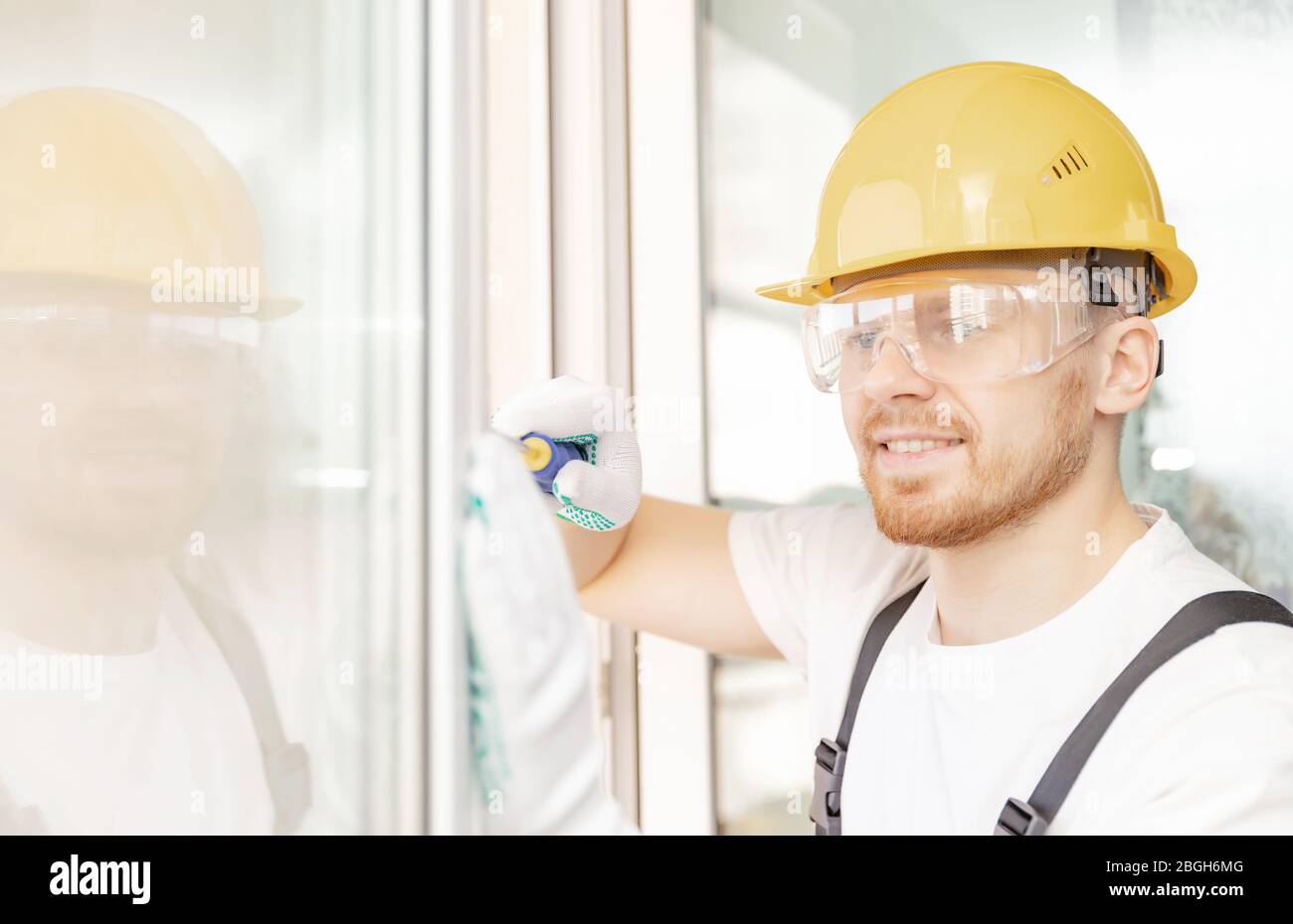 Worker in installing white plastic upvc window on house Stock Photo