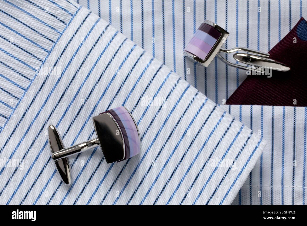 Striped white and blue men's shirt with multicolored cufflinks. Business dress code. Close-up. Selecrive focus. Stock Photo