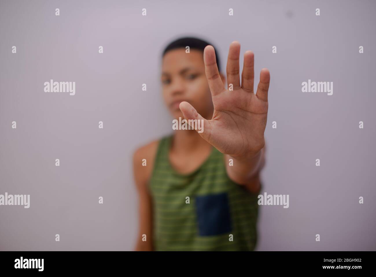 Selective focus of young boy holding up his hand to indicate stop Stock Photo