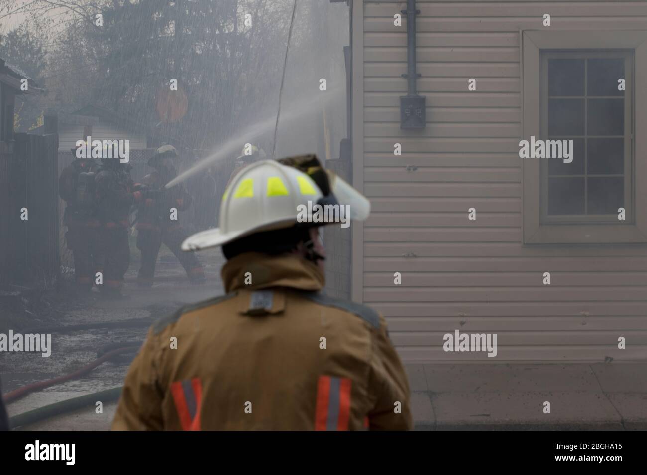 Fire fighters fighting fire started by arson. Containing the spread of residential house fire