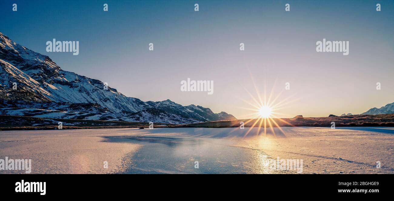 sunset on frozen lake in the high mountains Stock Photo