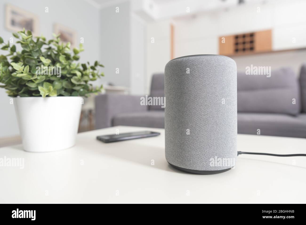 Smart speaker device in living room. Intelligent assistant in smart home system. Stock Photo