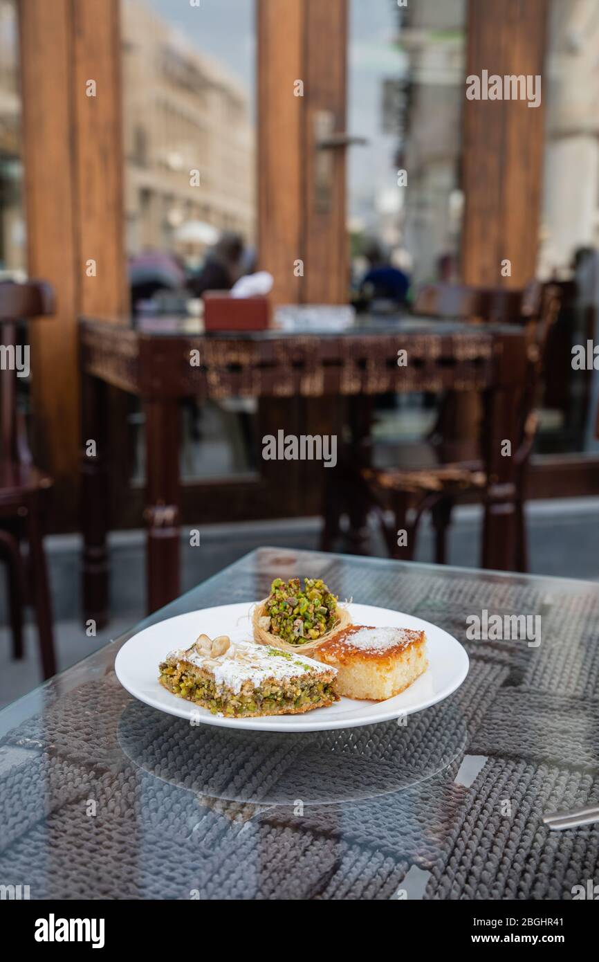 tasty arabic sweet dessert with pistachios on white plate in typical local cafe in Doha City