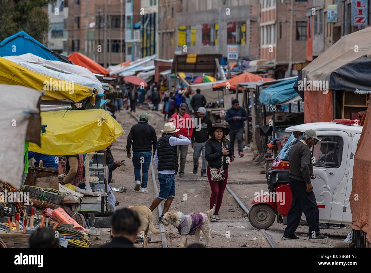 Local people going about their daily business and crossing the railway tracks as the train from Puno to Cusco passes through Stock Photo