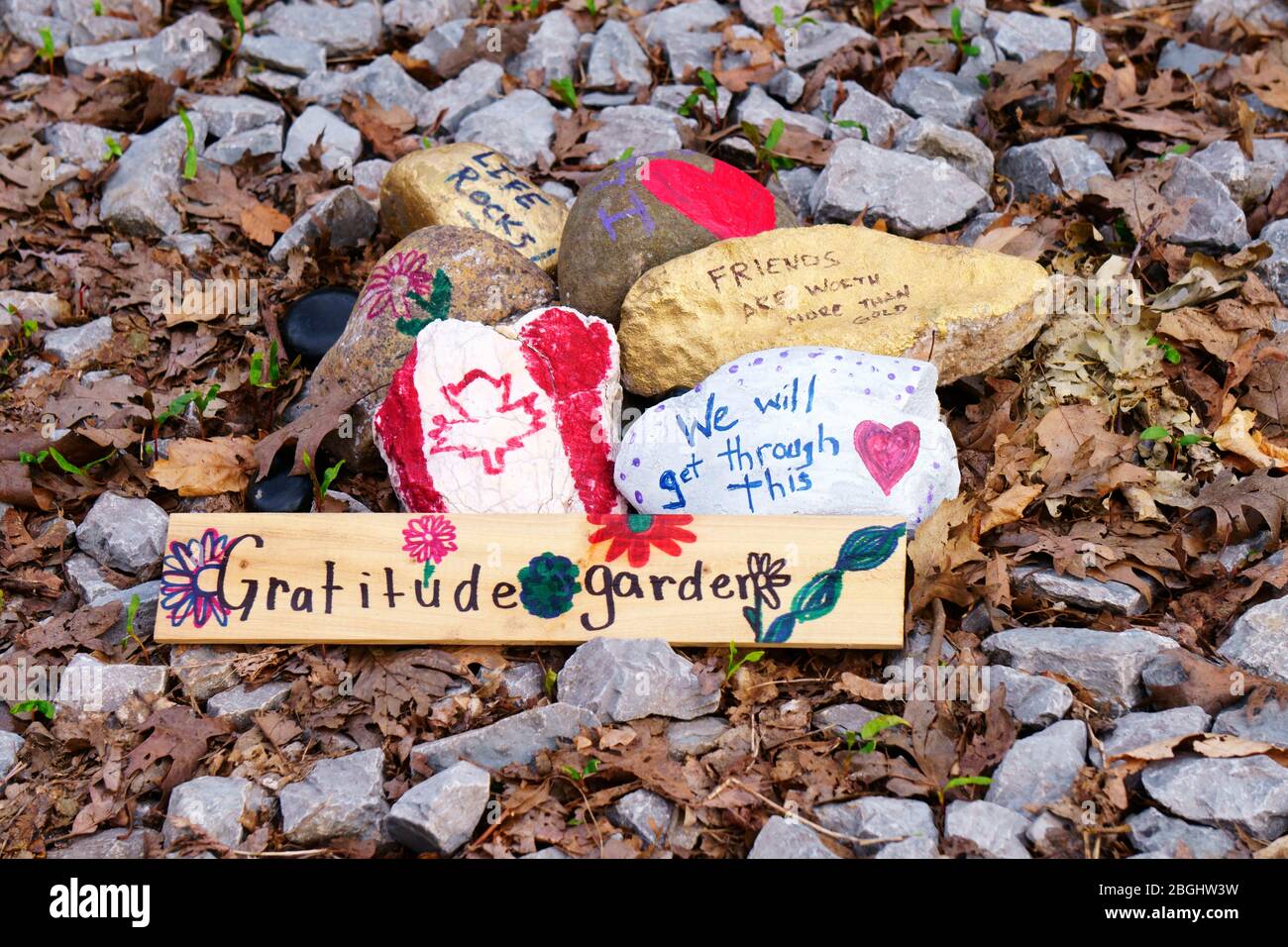 Rocks painted with encouraging words, hearts, flowers and Canadian Maple Leaf Flag, arranged by unknown people in midtown Toronto near an entrance to Moore Park Ravine trail during Covid-19 novel coronavirus outbreak. Photographed on April 20, 2020 Stock Photo