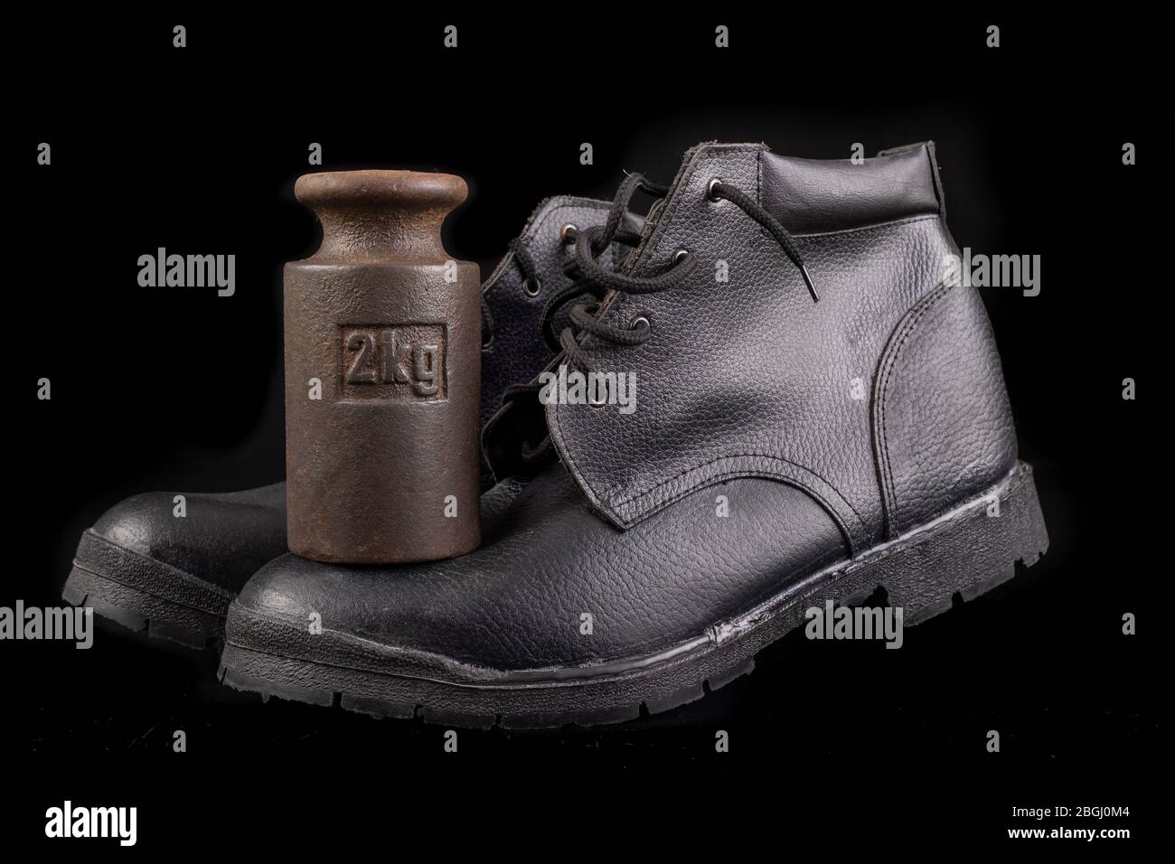 Black work shoe and 2 kg weight. Crush resistant shoes for production  workers. Dark background Stock Photo - Alamy