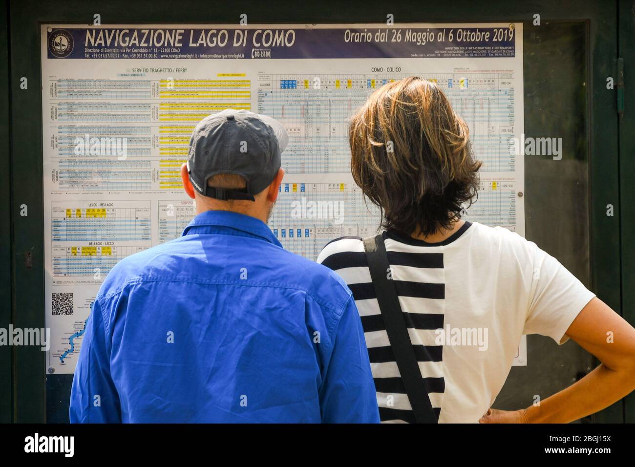 CADENABBIA, LAKE COMO - JUNE 2019: Man and woman studying the ferry timetable in Cadenabbia on Lake Como. Stock Photo