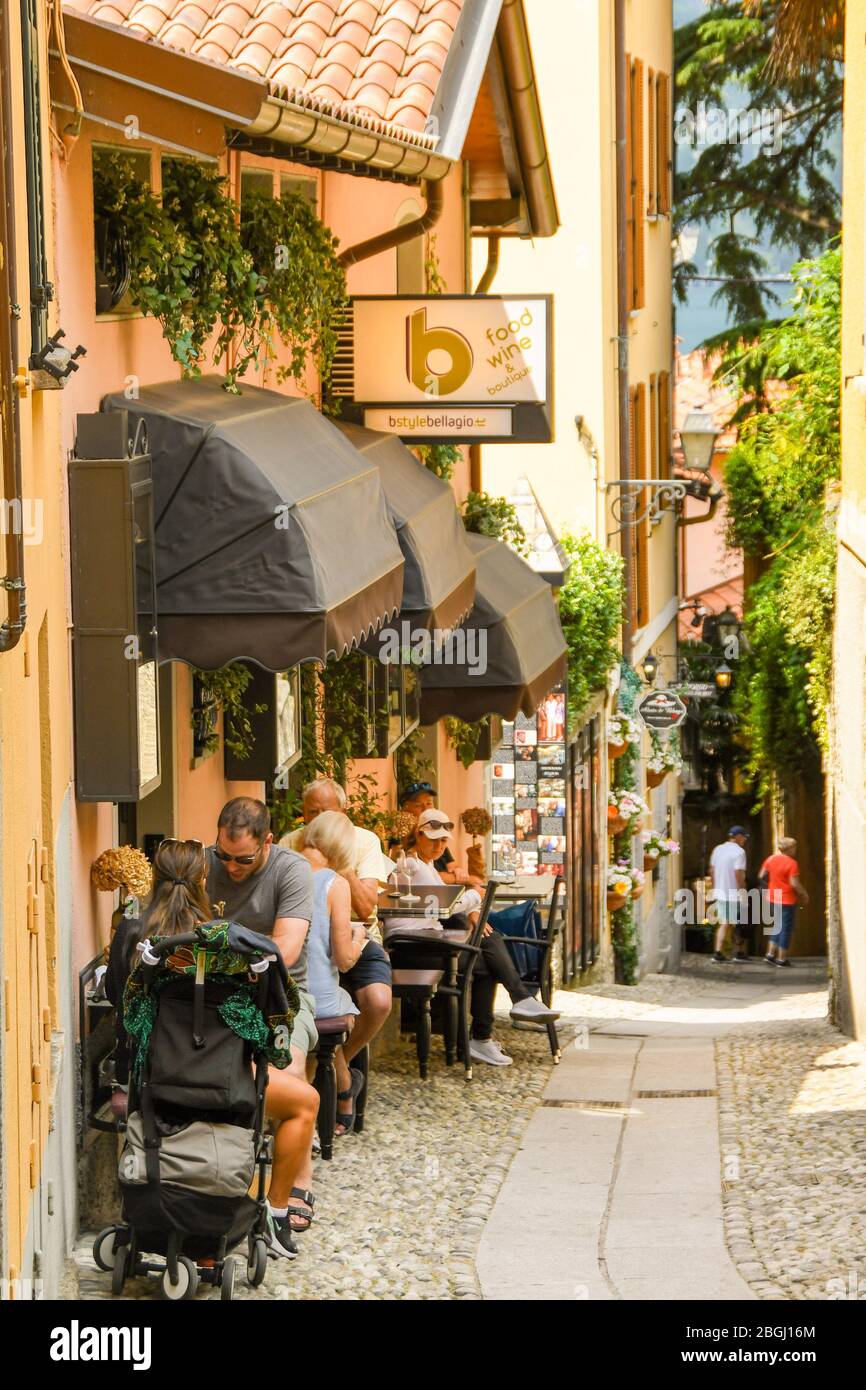 BELLAGIO, LAKE COMO, ITALY - JUNE 2019: People sitting outside a restaurant in one of the narrow streets of the town of Bellagio on Lake Como. Stock Photo
