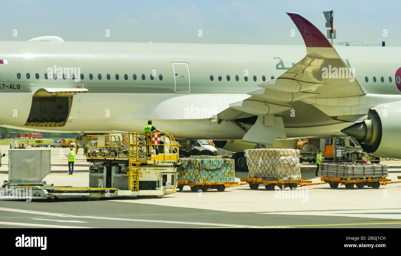 MILAN, ITALY - JUNE 2019: Ground handling equipment being used to load air freight into a Qatar Airways Boeing 787 Dreamliner aircraft at Milan Stock Photo