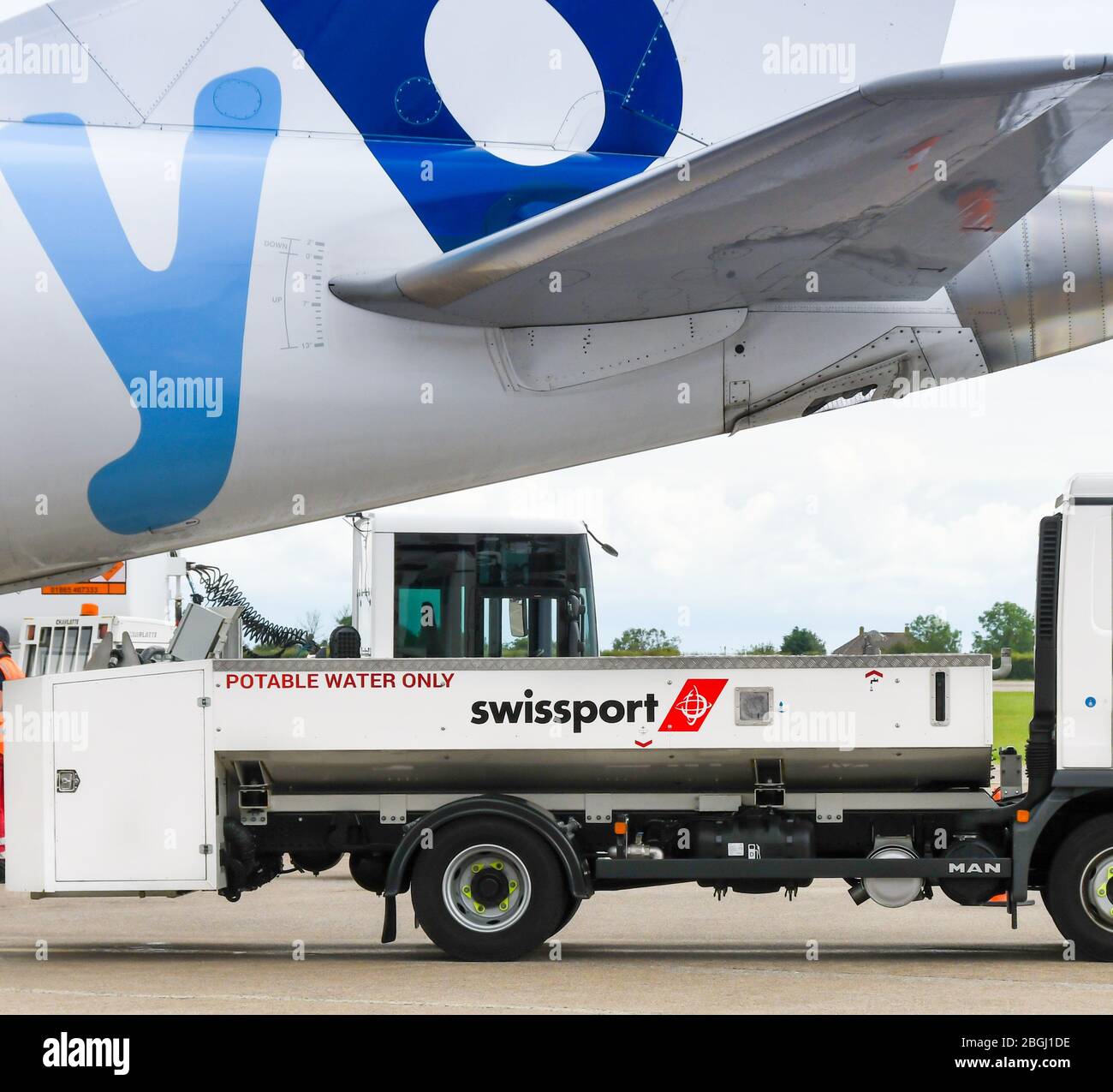 CARDIFF, WALES - JUNE 2019: Lorry for aircraft water supply servicing under the tail of a jet at Cardiff Wales Airport. It is operated by Swissport Stock Photo