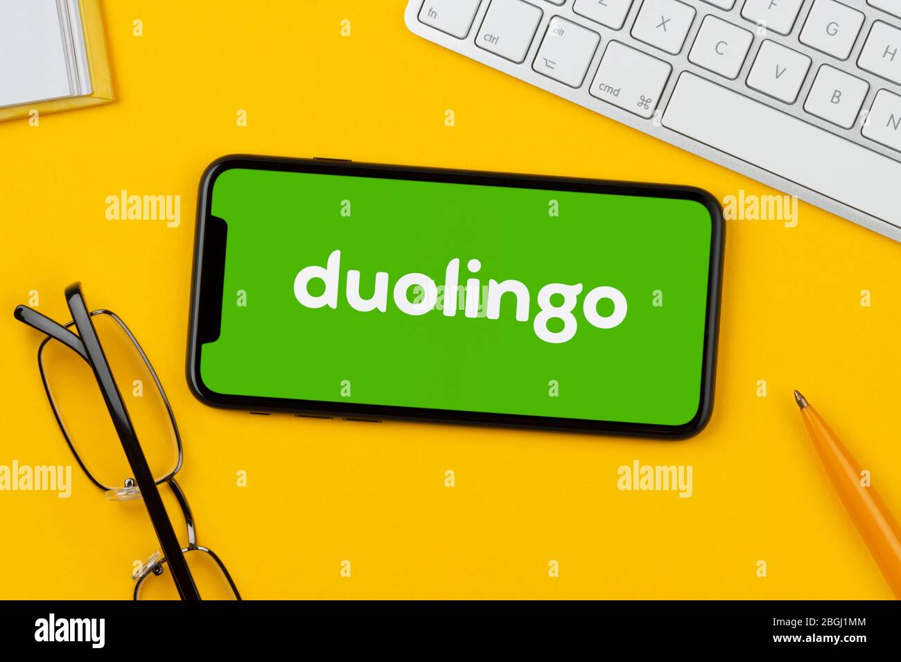 A smartphone showing the Duolingo logo rests on a yellow background
