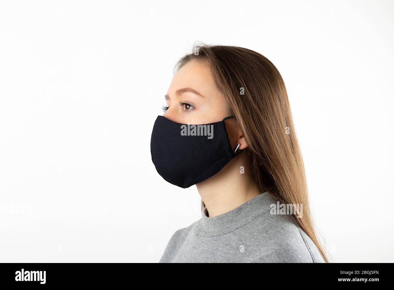 Portrait of young woman wearing black face mask isolated on gray ...