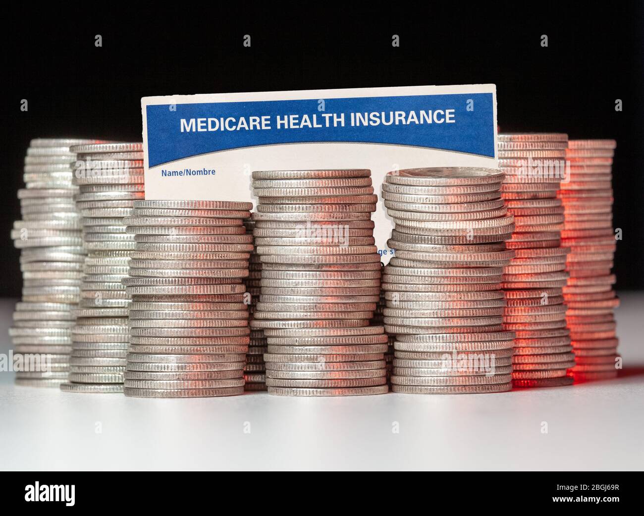 Many stacks of old silver dimes with medicare health insurance card to illustrate budget debt funding issues of the popular program Stock Photo