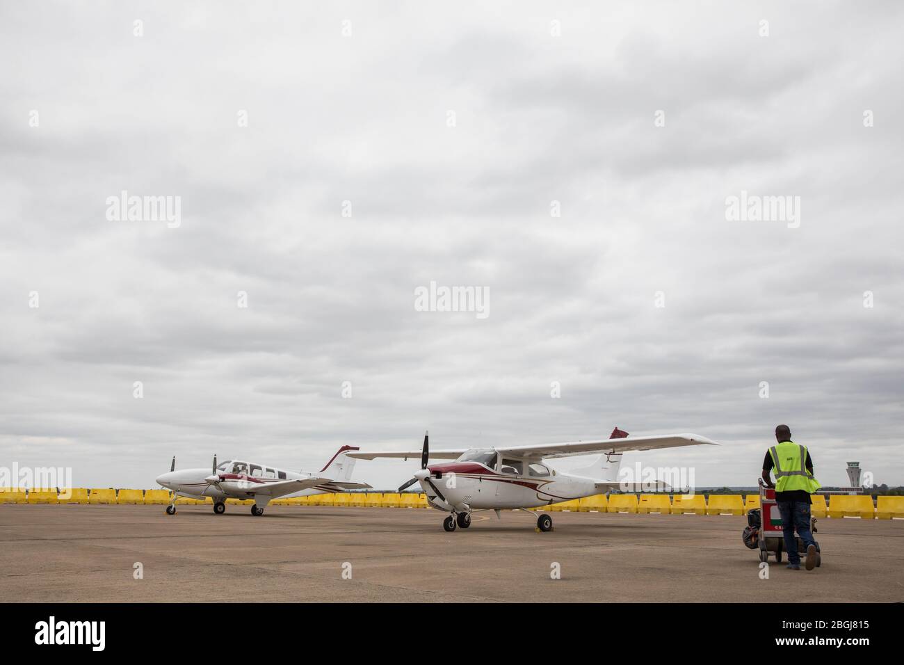 A luggage handler takes luggage to small plane for safari travel from Lusaka airport, Lusaka Province, Zambia. Stock Photo
