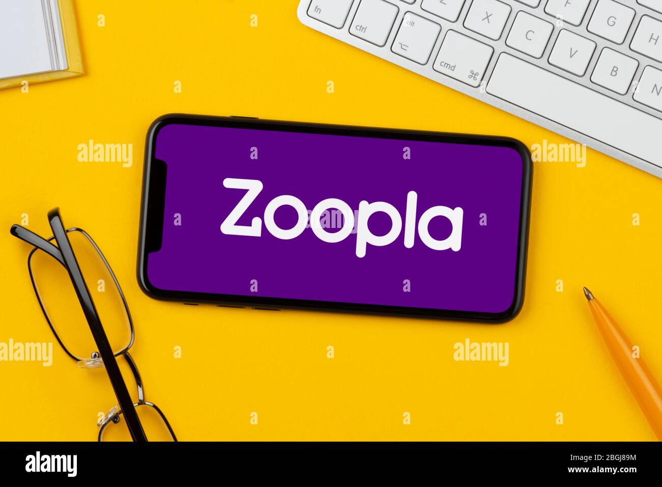 A smartphone showing the Zoopla logo rests on a yellow background along