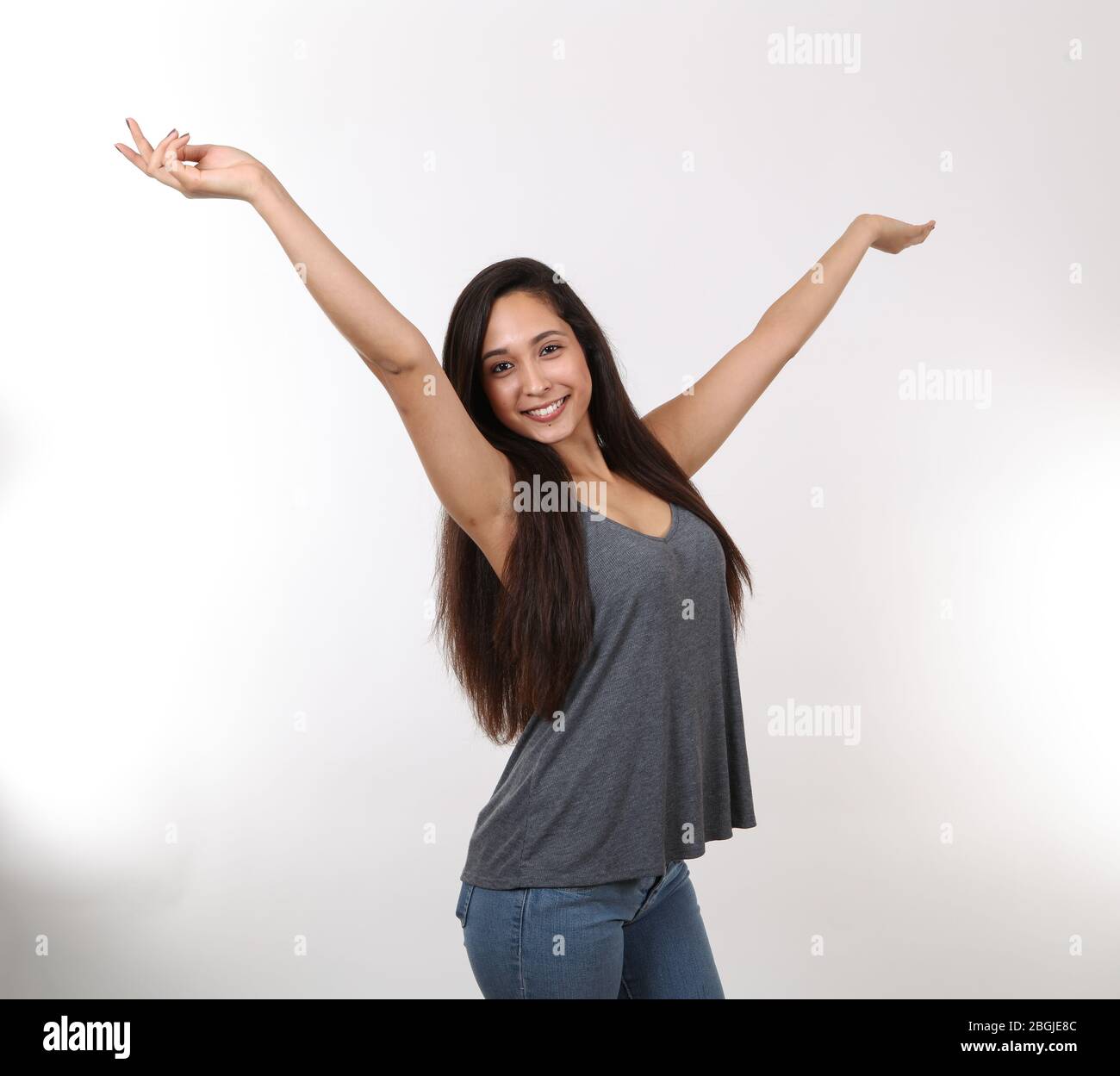 An excited hispanic young girl throws her hands in the air with excitement. Stock Photo