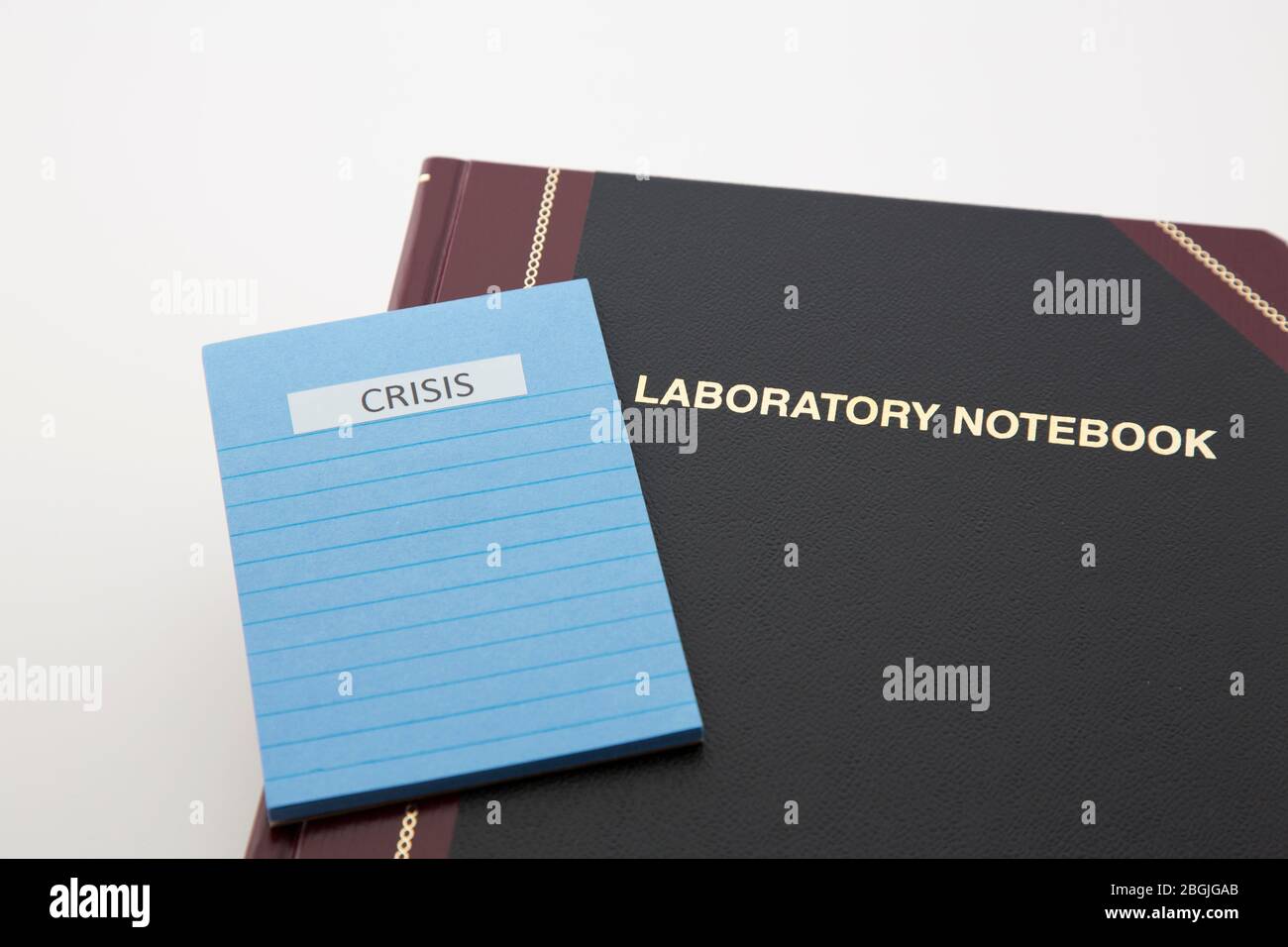 Importance of scientific research and hard data during crisis emphasized by Laboratory Notebook and pad with CRISIS lettered at top. Stock Photo