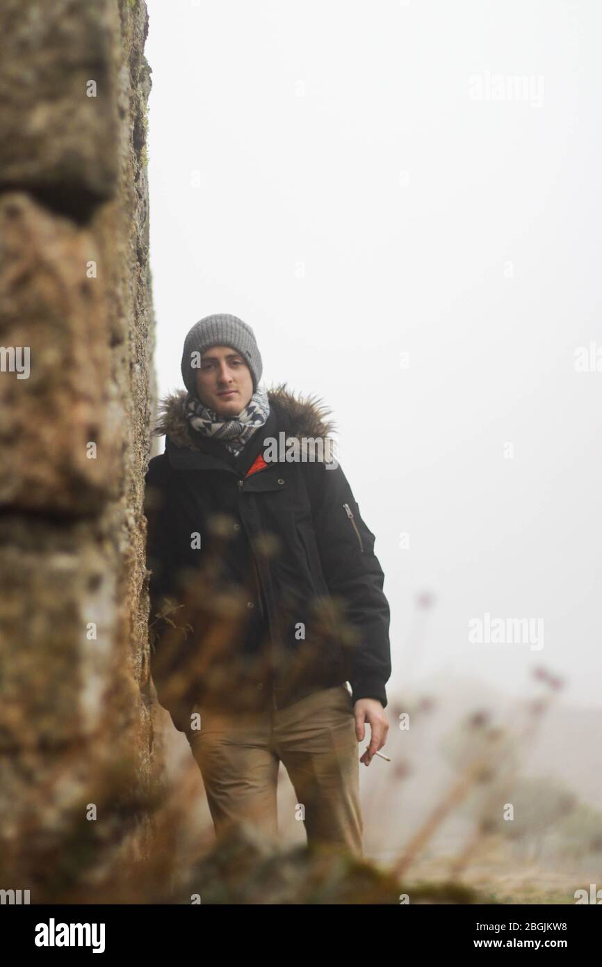 young boy with beanie and cigar leaning on stone wall Stock Photo