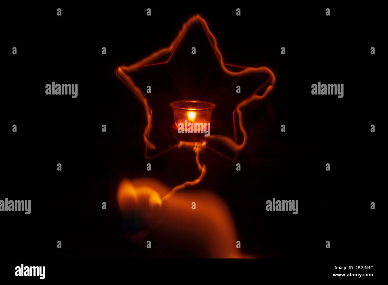 Star-shaped iron burning candle around in the dark background Stock Photo