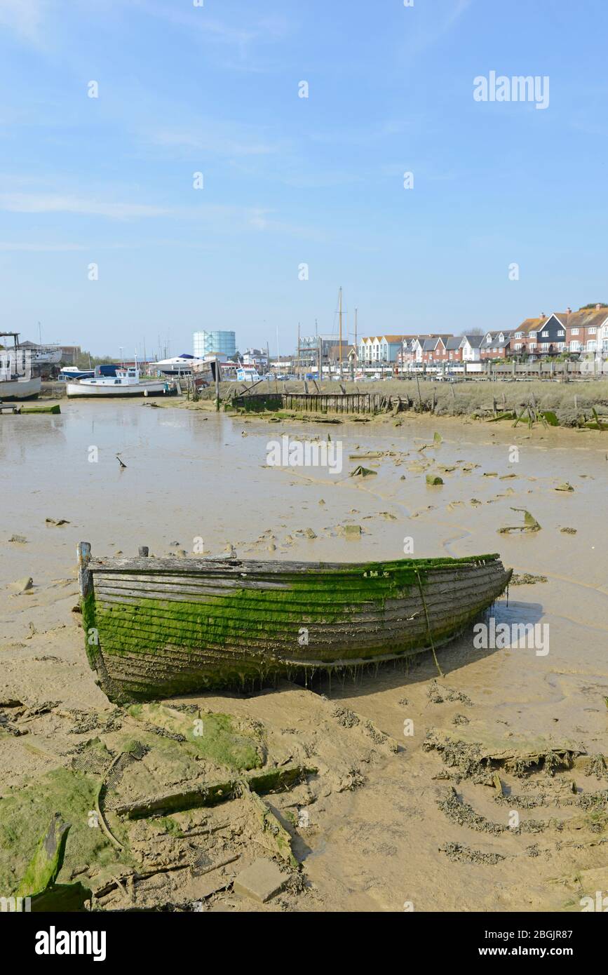 A disused rowing boat standing on the mud in Littlehampton harbour at low tide. West Sussex, UK