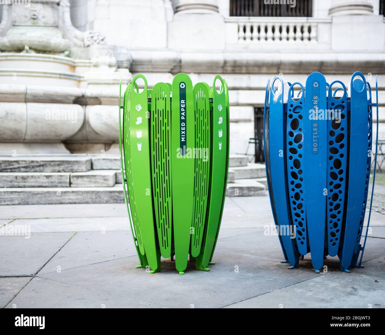 Recycle cans in bright green and blue in an urban area for mixed use. Stock Photo