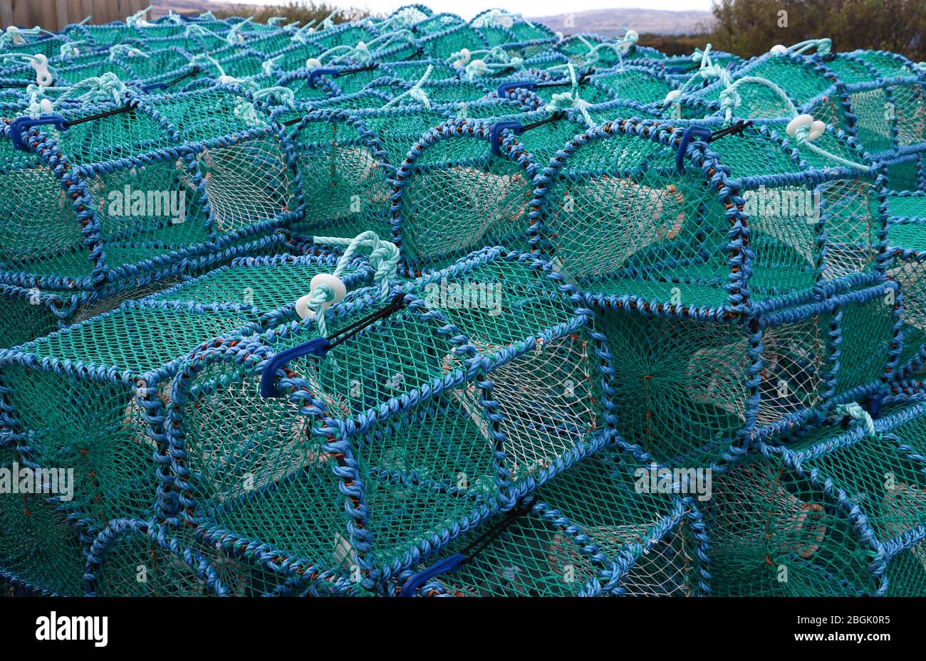 Stacks of blue Scottish crab pots or creels, used to trap crabs, on a dock on the Isle of Mull, Scotland. Old creel fishing tradition.Marine industry. Stock Photo